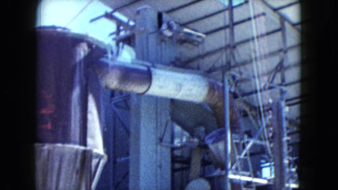 Industrial drum, pipework, tower frame, and roof structure seen through 8mm film borders.
