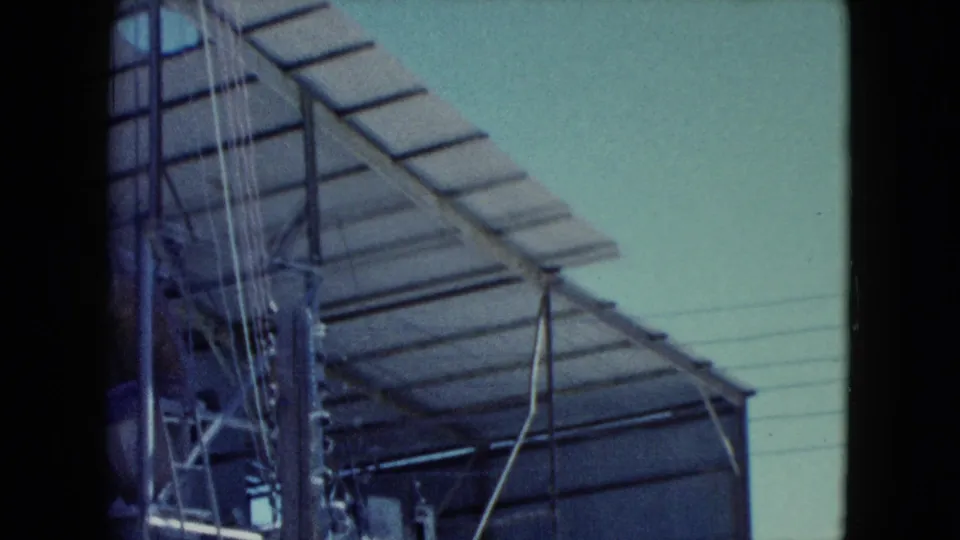 1960 Nevada industrial frame showing metal tower framing, hanging cables, pipework, and slatted roofing from a low angle.