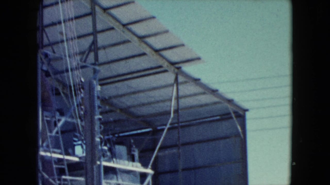 1960 Nevada 8mm frame showing a corrugated metal structure, roof framing, power lines, and dark film borders.