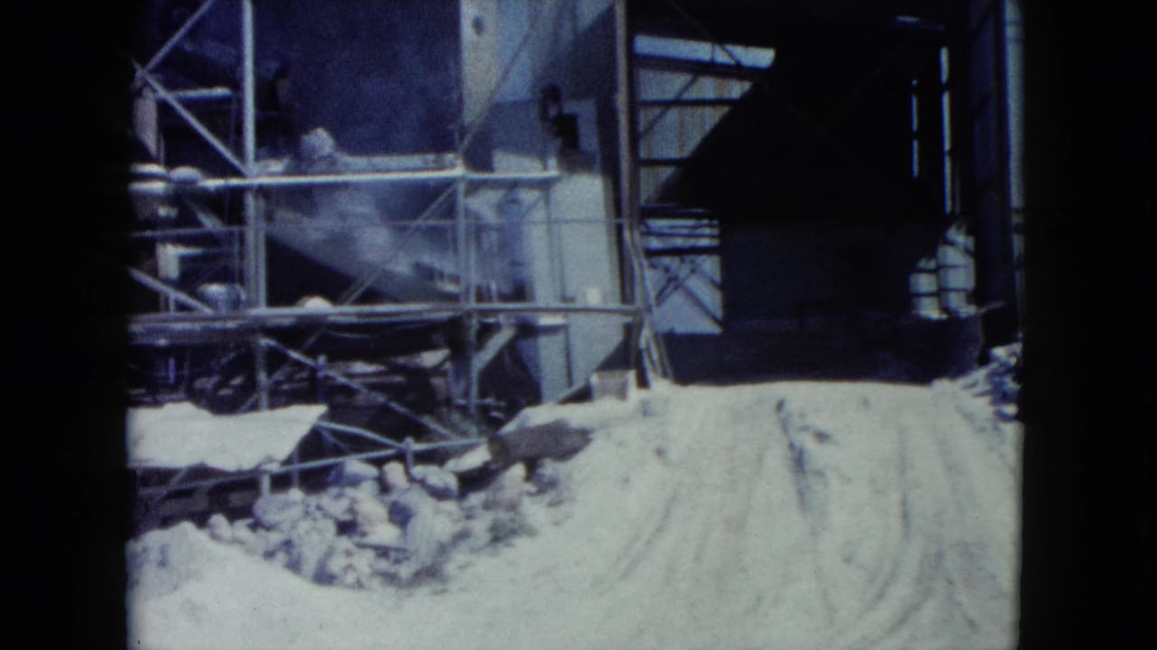 Construction site with sand piles, scaffolding, and dark building openings.