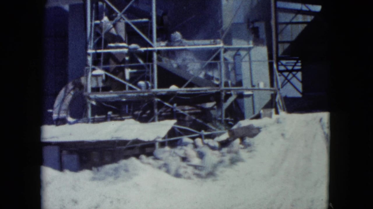 Industrial scaffolding and sand piles beside a tall structure.