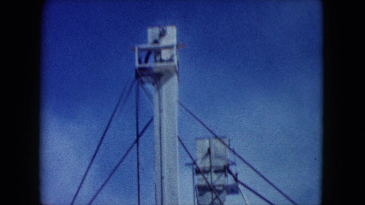 Tall white tower with support cables against a blue sky.