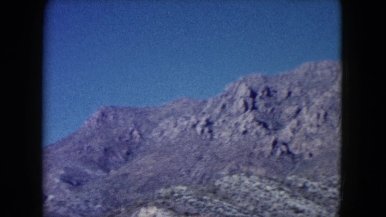 Rugged gray-brown mountain ridge beneath a clear blue sky.
