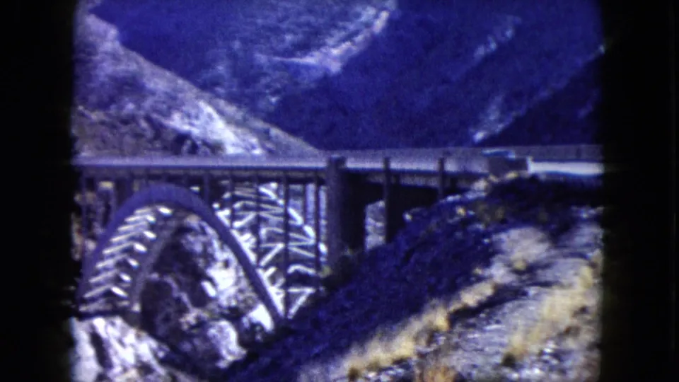 1960 Nevada 8mm frame showing an arched canyon bridge set among steep rocky hills.