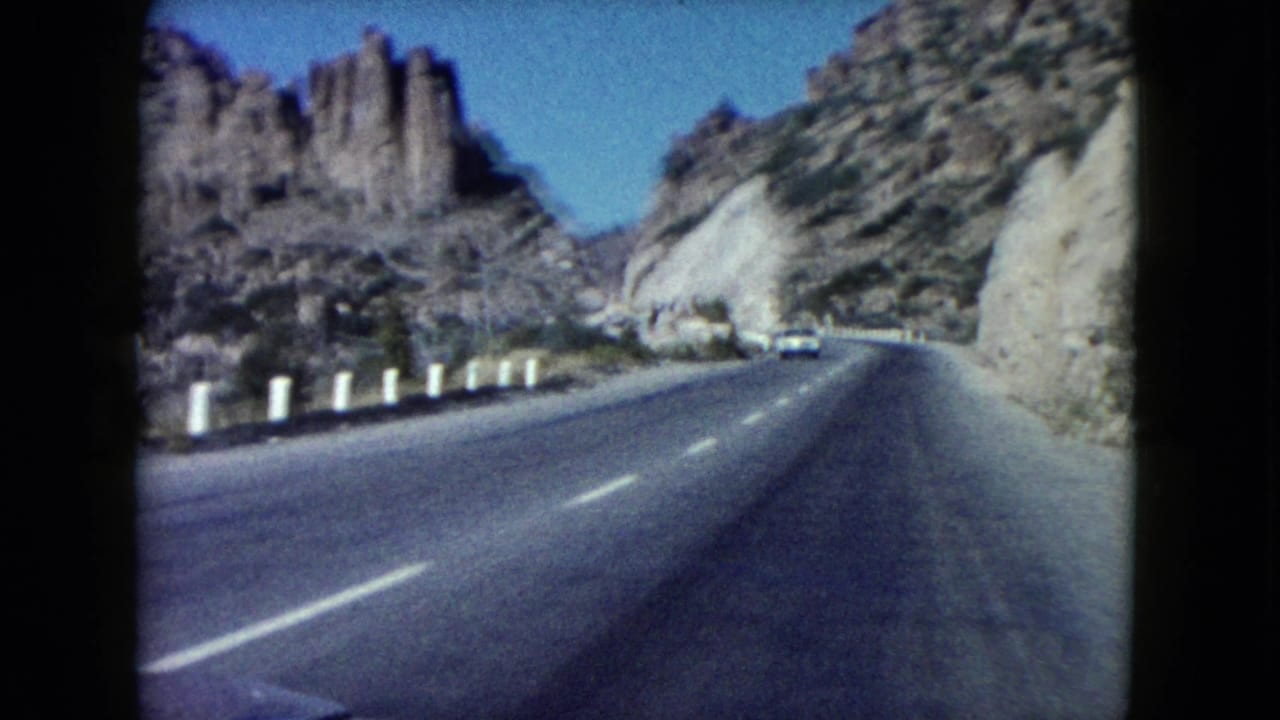 Forward-facing 8mm road view in Nevada, with a paved highway bending through dry rocky canyon scenery.
