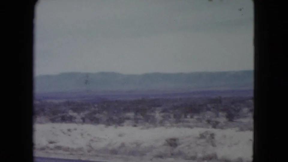 Soft 8mm view of Nevada desert scrub and distant mountain ridges, likely filmed while traveling.