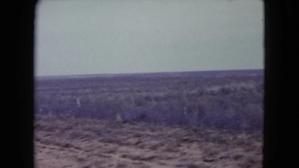 1960 Nevada 8mm frame showing sandy ground and dry scrubland, with the horizon slightly tilted in handheld framing.