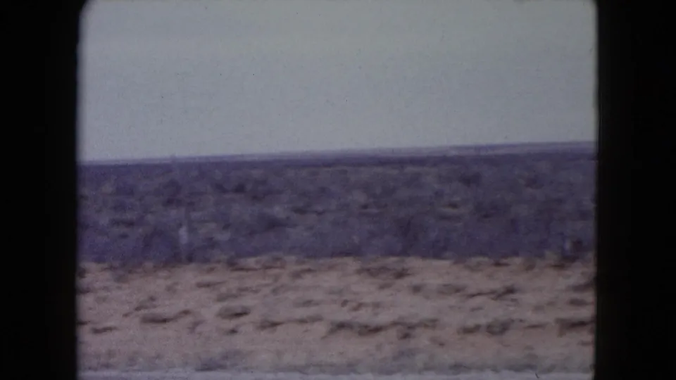 Soft 8mm view of Nevada desert terrain with sparse brush, pale sky and no visible people or structures.
