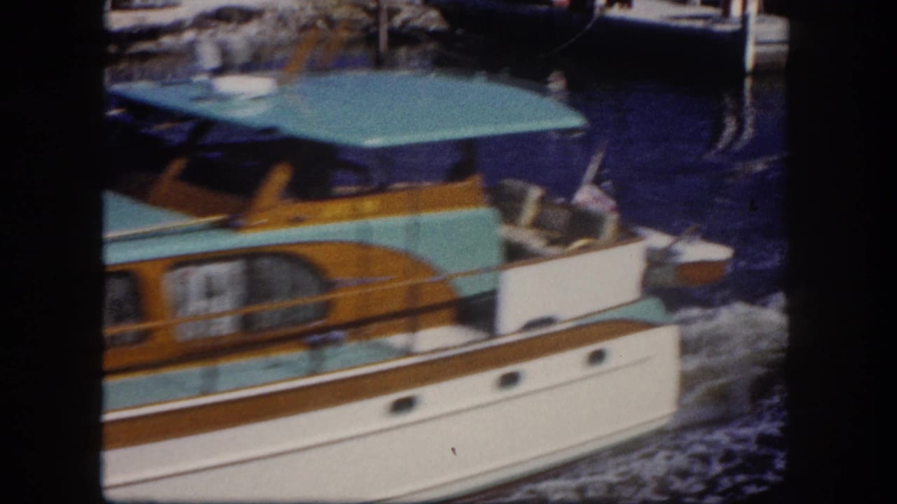 Turquoise and white motorboat passing close to camera on a waterway.