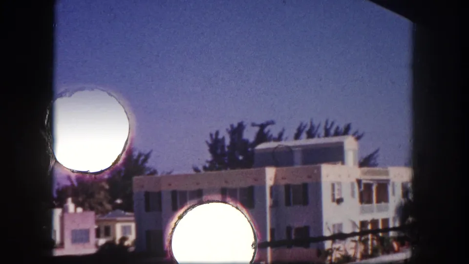Closer 8mm view of a light modernist building in Tampa, partly obscured by film borders and circular contact-sheet exposure marks.