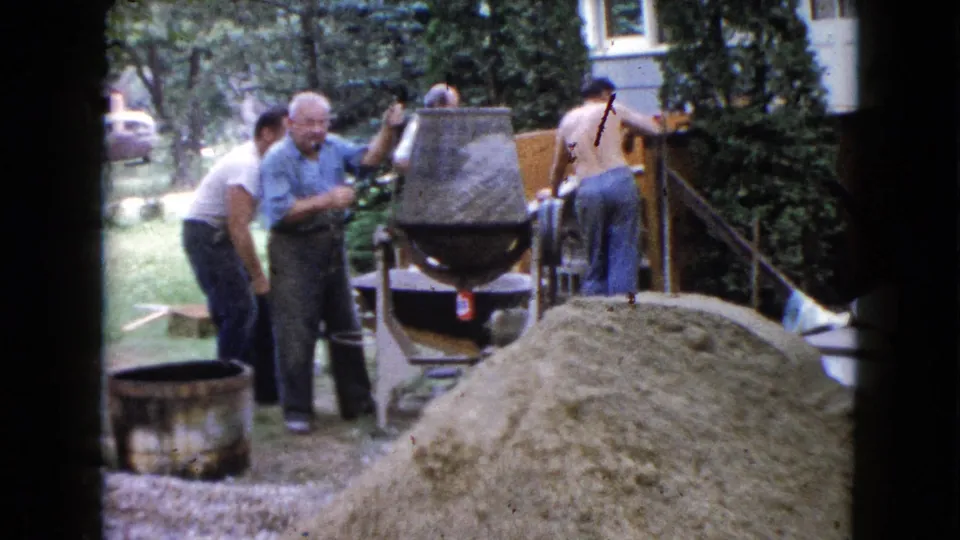 A man handles the cement mixer as other men stand nearby during 1960 backyard construction work in Wauconda, Illinois.