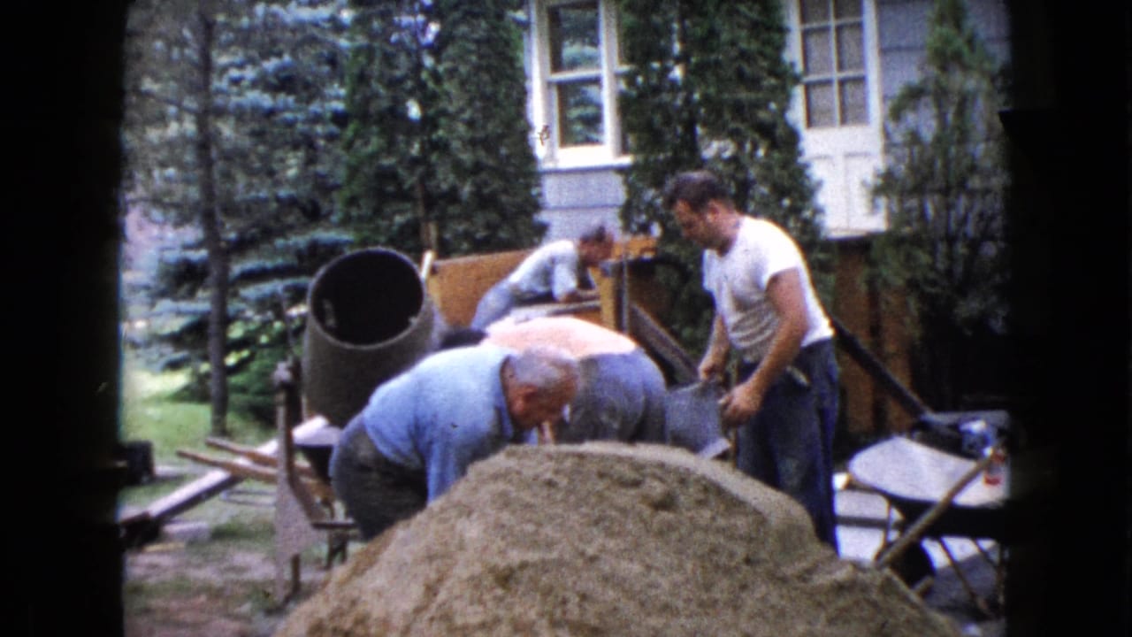 Men continue working around a sand pile, buckets, and concrete mixer.