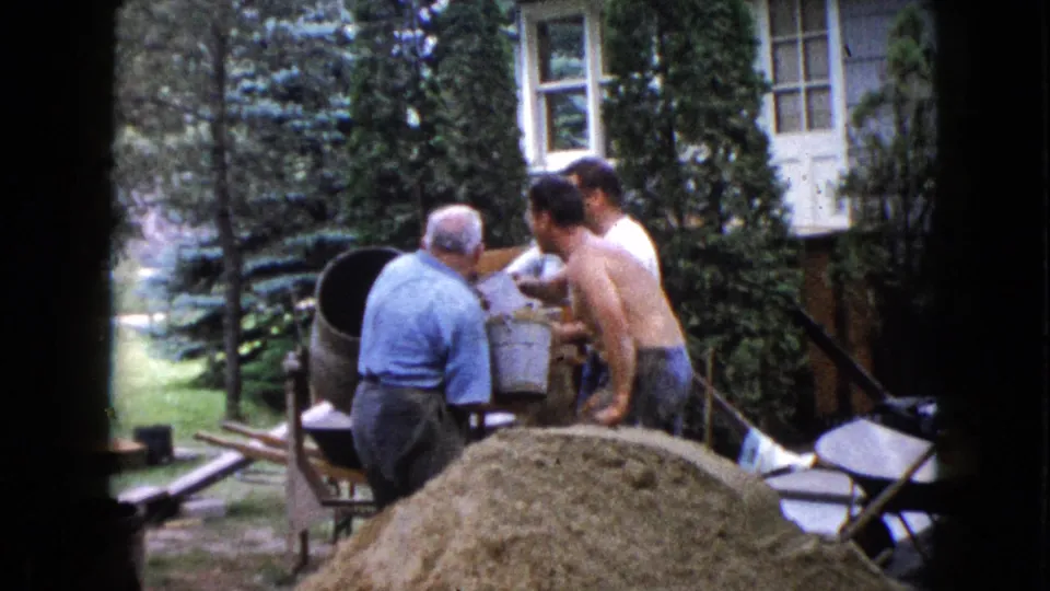 Three adult men cluster near a cement mixer in a suburban Wauconda backyard, with a sand pile in the foreground.