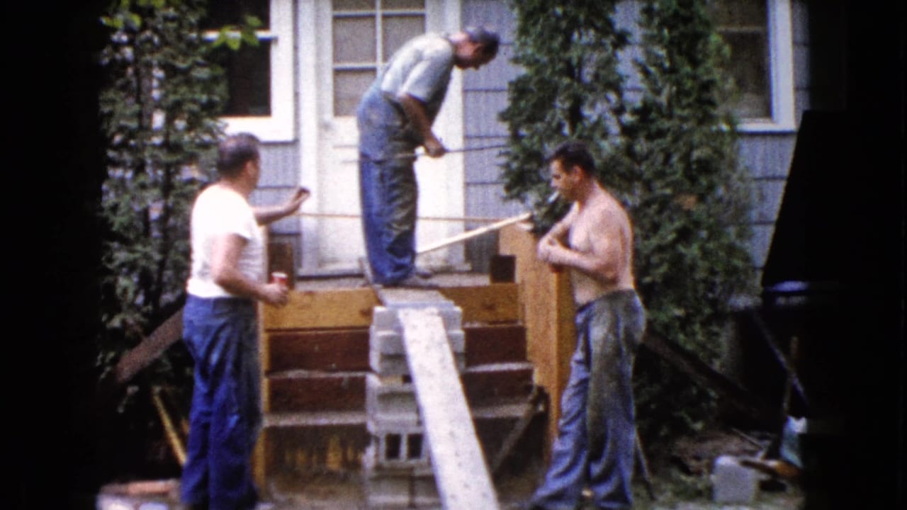Three adult men work around wooden porch steps in front of a house.