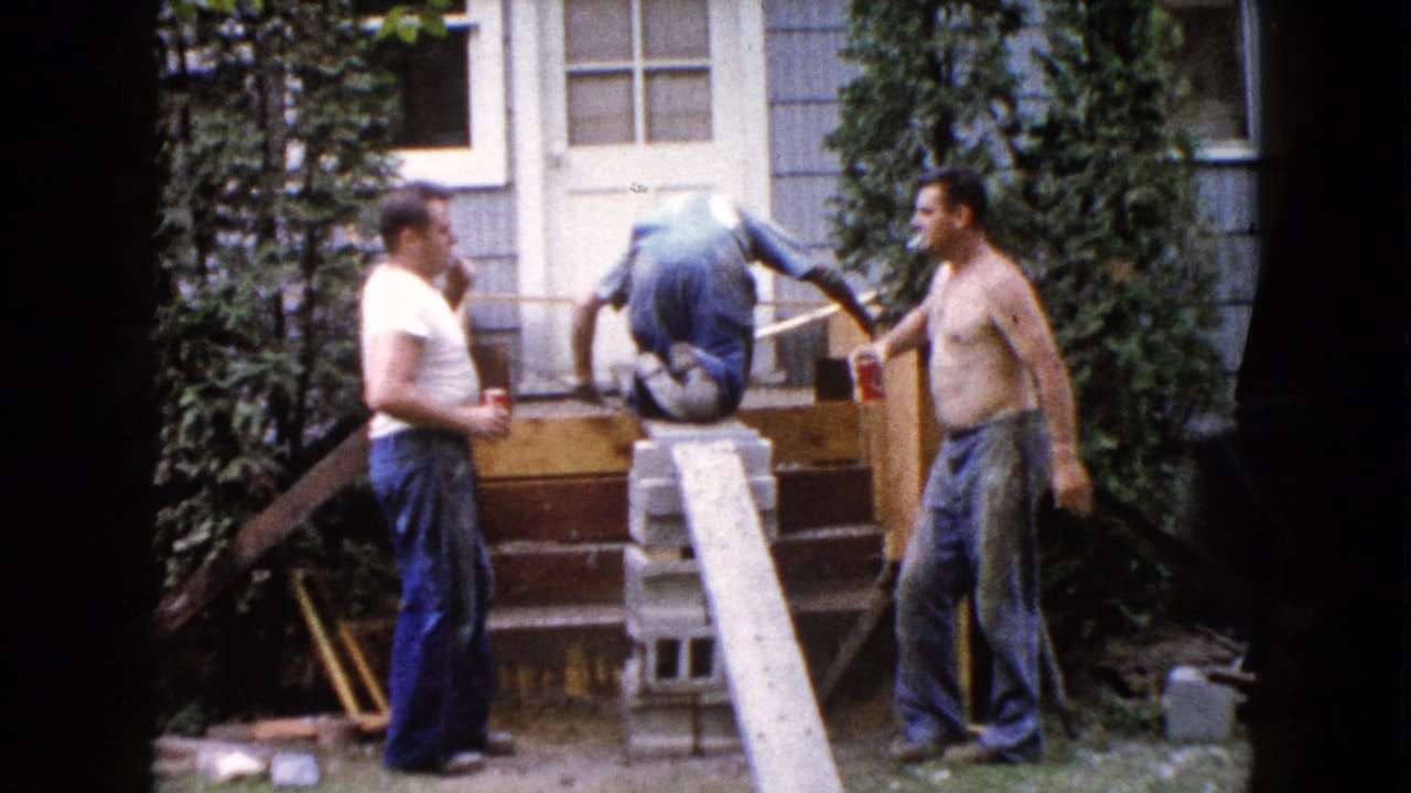 Three adult men stand and work around wooden backyard steps beside a house.