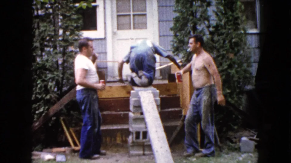 In Wauconda, Illinois in 1960, three adult men gather around a partly built wooden staircase with cinder blocks and a plank in a backyard.