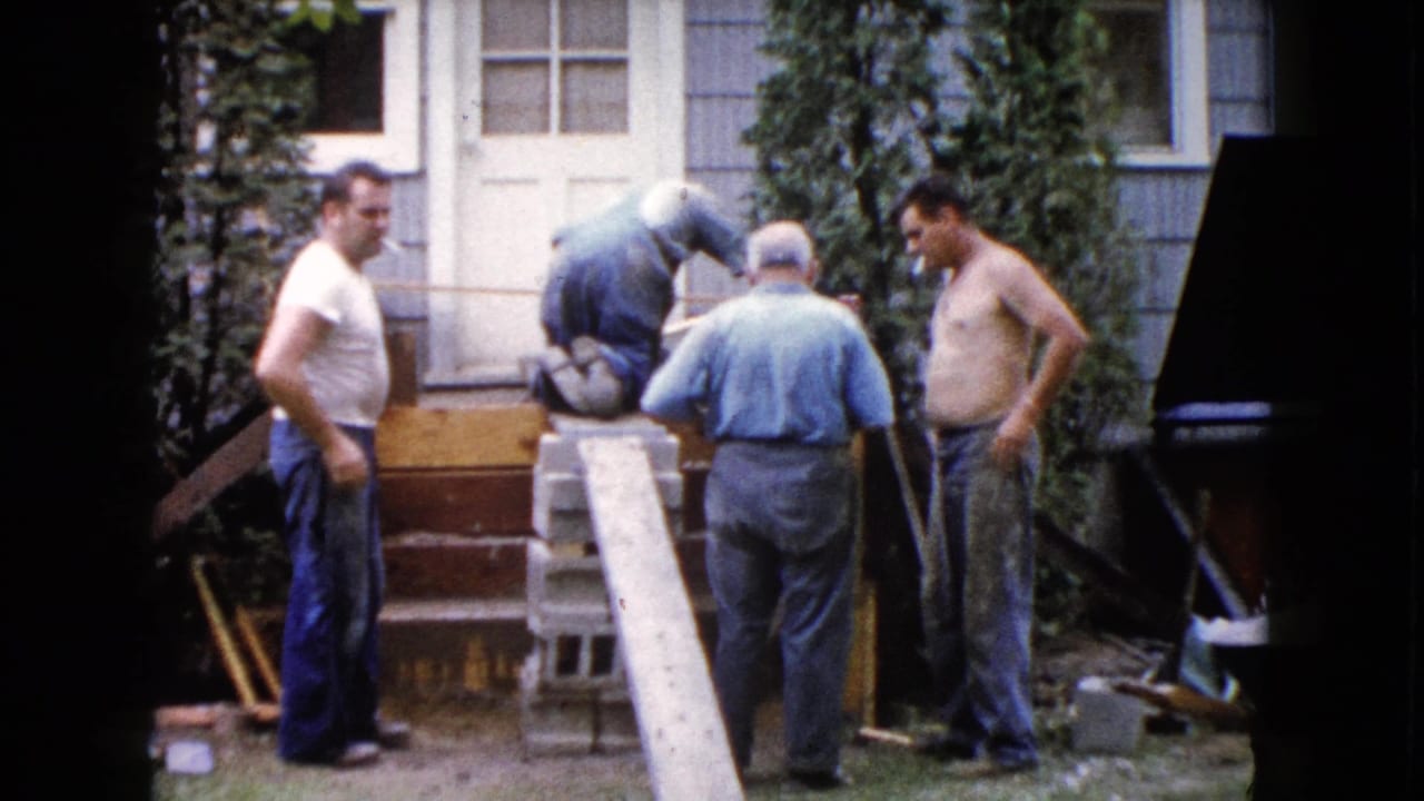 In Wauconda, Illinois in 1960, four adult men stand and work around a house entrance during deck construction.