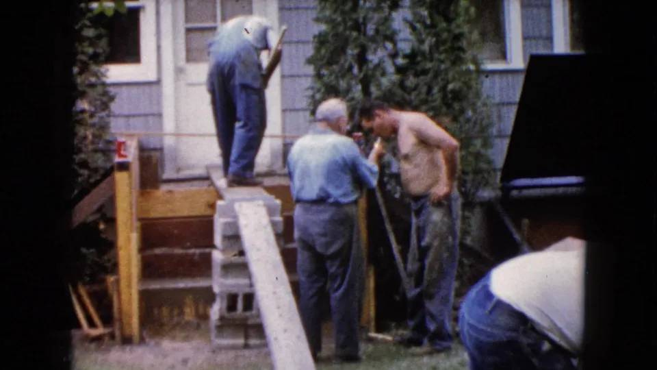 At the end of the 1960 Wauconda clip, men remain around the deck work area beside the house entrance.