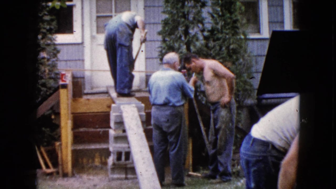 Adult men work on porch steps outside a house in Wauconda, Illinois, in 1960, with shovels, lumber, and cinder blocks visible.