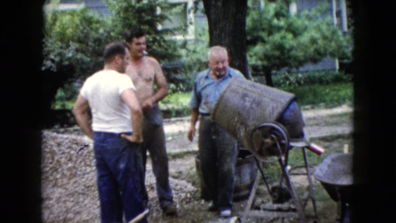 Three adult men stand near a cement mixer in a Wauconda backyard, with one shirtless man joining the work area.