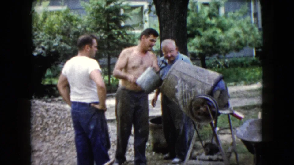 Three adult men remain beside the cement mixer, with a bucket and wheelbarrow visible in the Wauconda backyard.