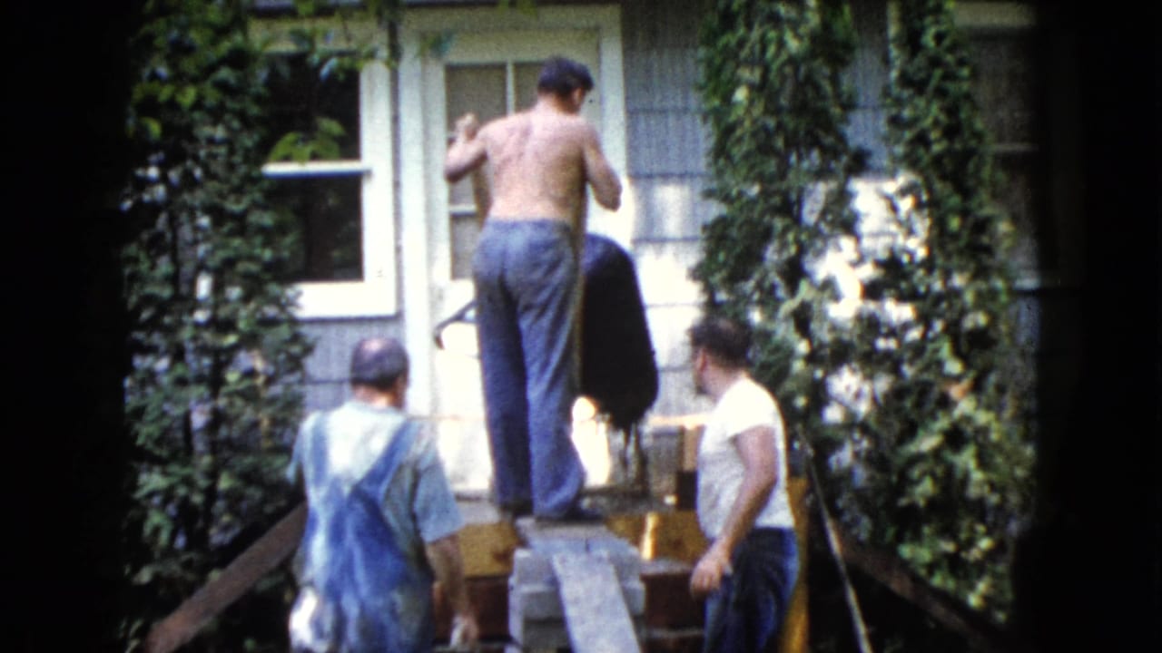 Men working on a house exterior beside ivy and windows.