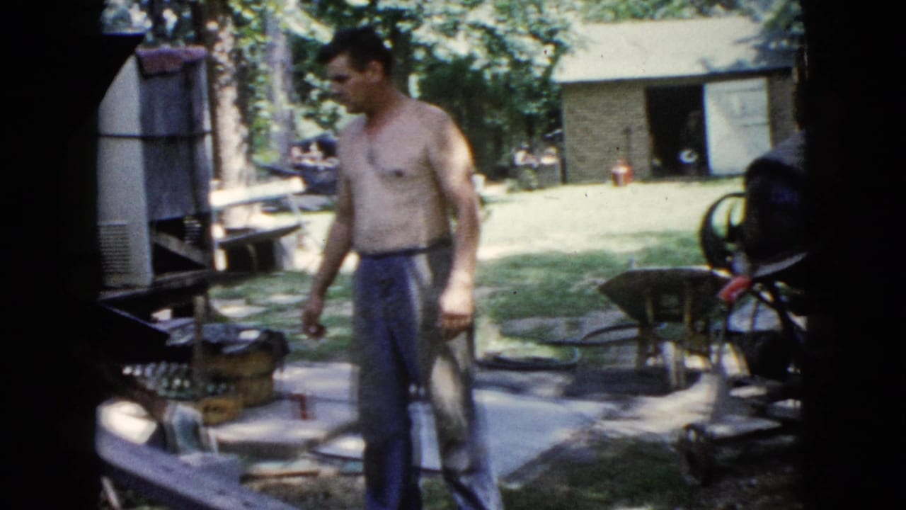 In Wauconda, Illinois, a shirtless man stands beside backyard work materials and a wheelbarrow in 1960 home-movie footage.