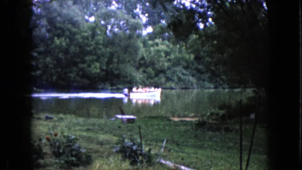 The boat continues across the lake in Wauconda, Illinois, framed by grass, reeds, and dense trees.