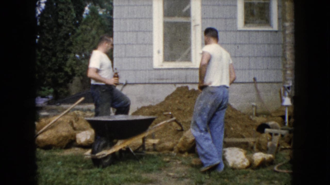 In Wauconda, Illinois, 1960, one man holds a bottle while another stands by a dirt pile near a house.