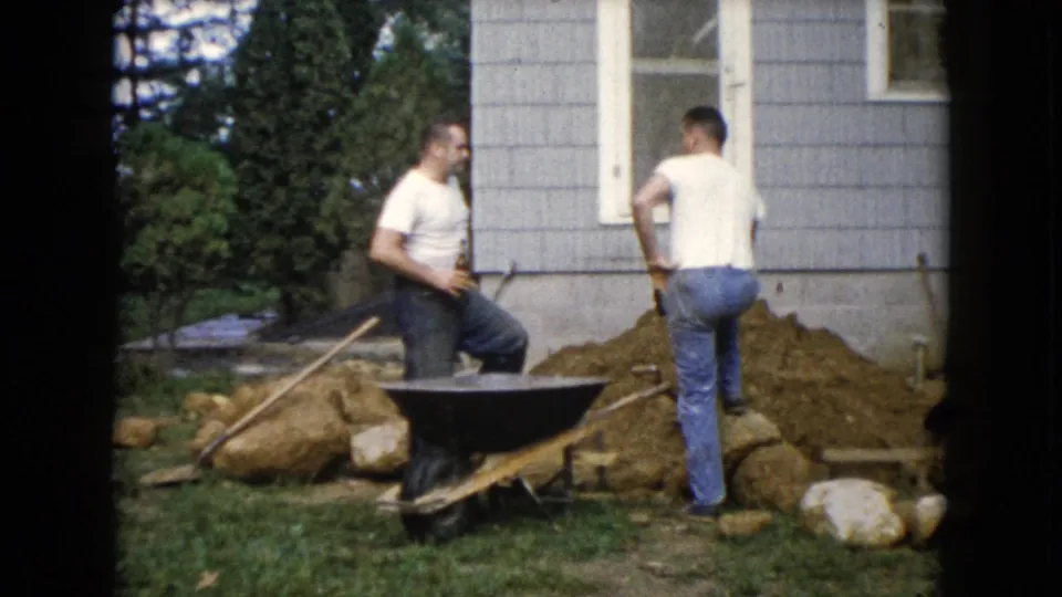 In Wauconda, Illinois, 1960, one man steps near a dirt pile while another watches beside the wheelbarrow.