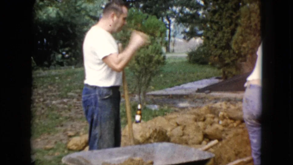 In the Wauconda yard scene, an adult man looks down with a shovel beside a wheelbarrow, earth piles, and trees.