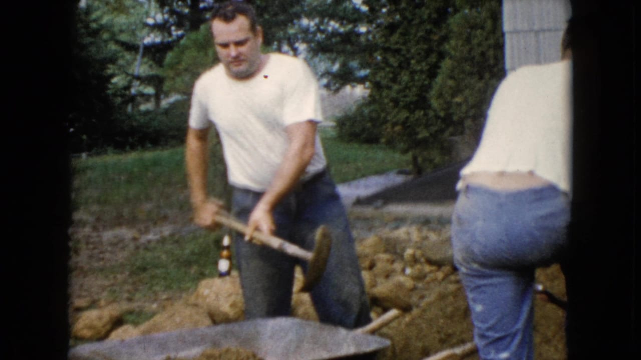 In Wauconda, Illinois, 1960 home-movie footage, two adult men dig a trench beside a house with shovels and a wheelbarrow nearby.