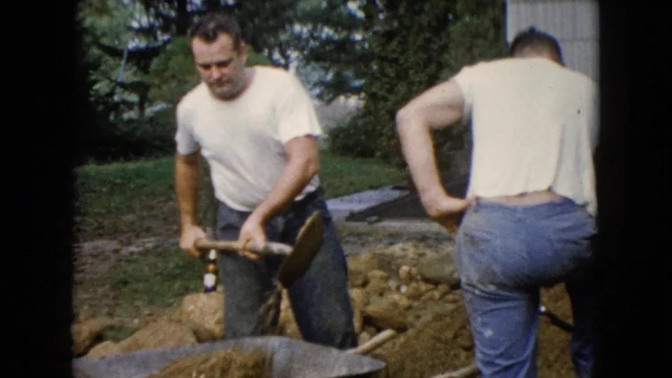 A 1960 Wauconda frame shows a man handling a shovel at a wheelbarrow, with another man standing at the edge of the work area.