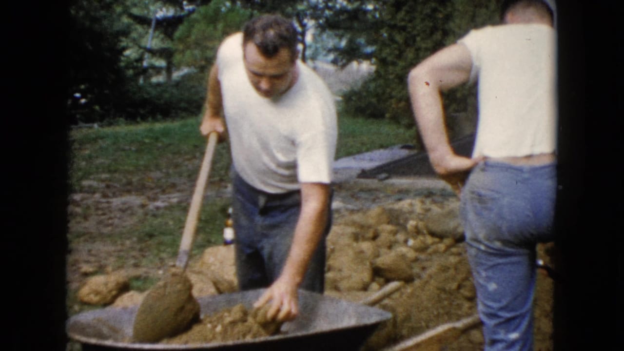 1960 Wauconda backyard construction frame with a man shoveling soil and another adult man seen from behind.