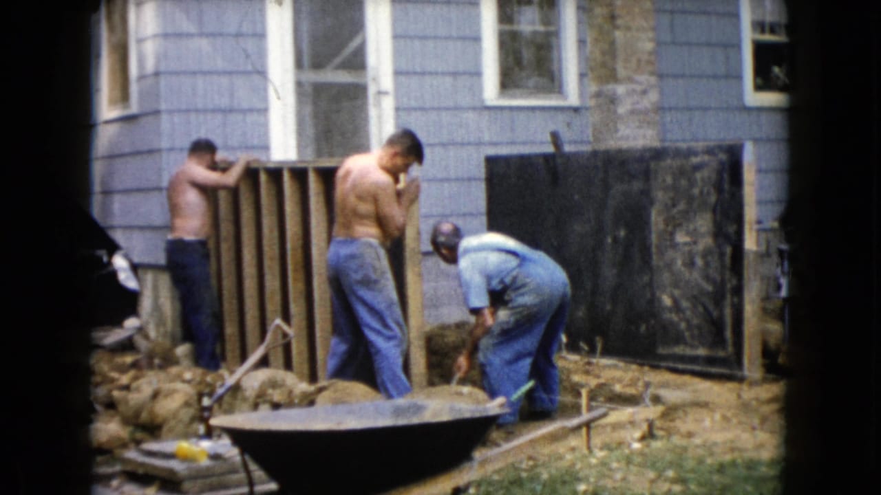 1960 Wauconda backyard scene with two shirtless men by a wooden frame and a third man in overalls working near soil.
