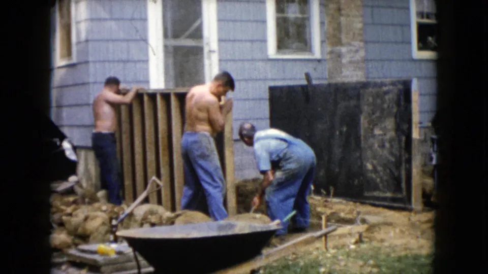 1960 Wauconda backyard scene with two shirtless men by a wooden frame and a third man in overalls working near soil.