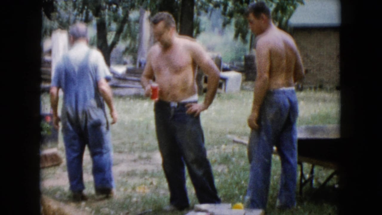 Three adult men in a Wauconda yard appear to take a work break, with red cups, trees, boards, and an outbuilding in view.