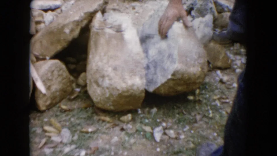 Close 8mm frame of a hand examining large rocks at the Wauconda, Illinois outdoor work site in 1960.