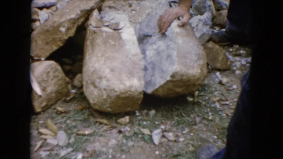 The final frame shows a worker's hand and boot beside large stones in the 1960 Wauconda, Illinois construction footage.