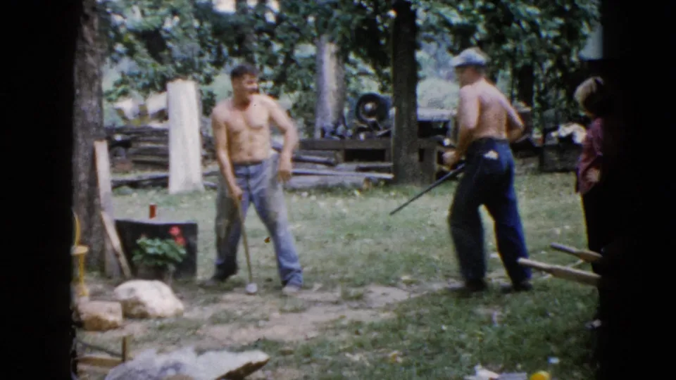 At the end of the Wauconda yard clip, the sledgehammer user steps back as the man in a cap moves with a long tool nearby.