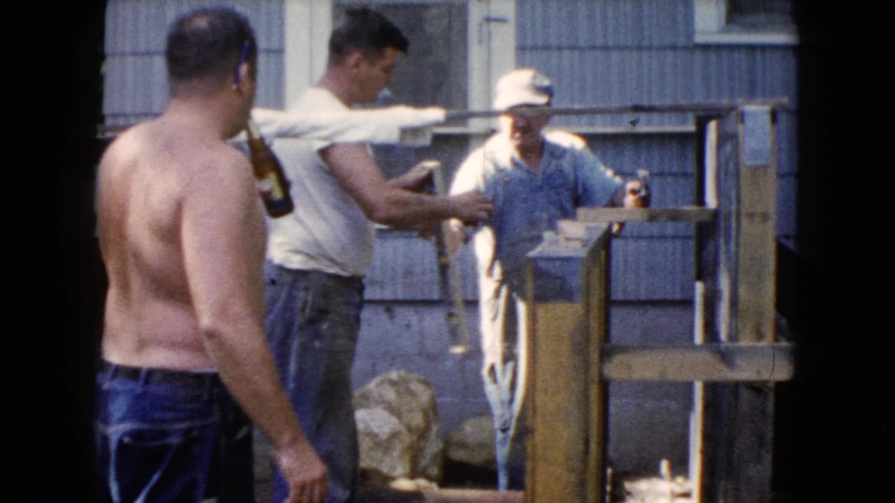 A 1960 Wauconda backyard work scene shows men handling or discussing a wooden structure while one holds a beer bottle.