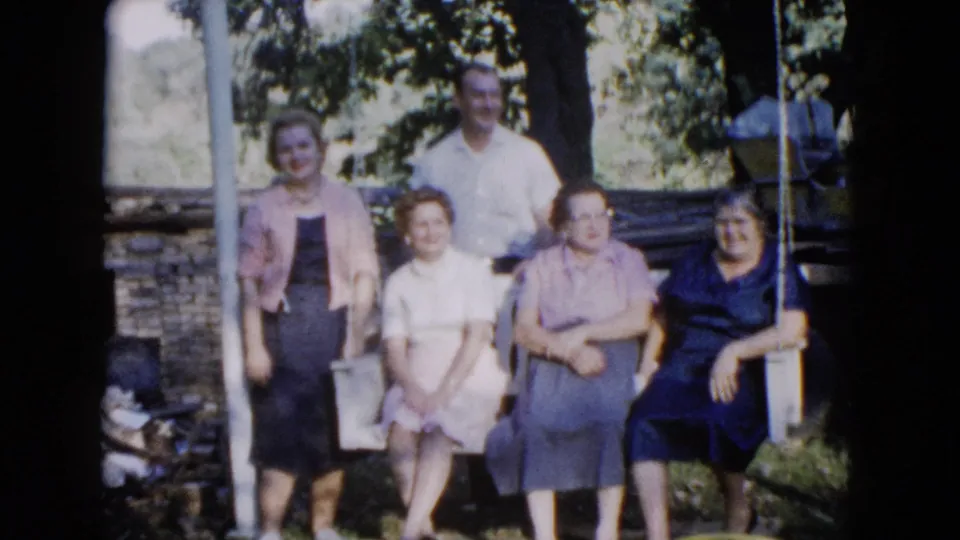 Five adults continue posing outdoors in the 1960 Wauconda garden scene, with seated figures in front and a man standing behind.