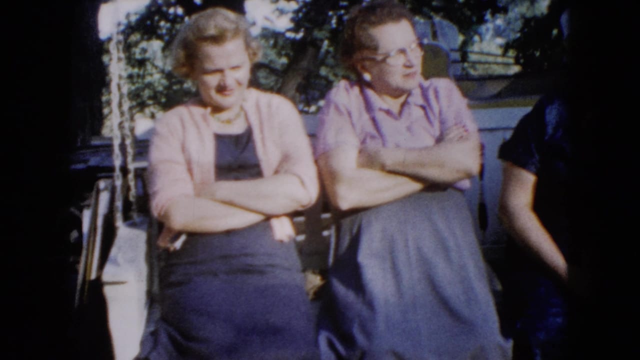 1960 Wauconda frame with two women seated on a shaded porch swing and another person partly cropped at right.