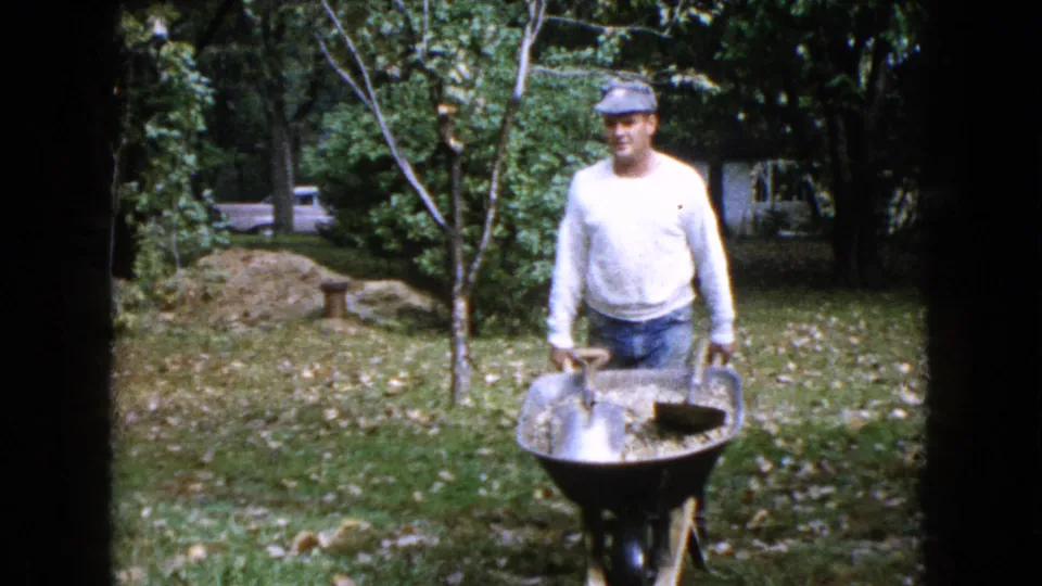 The final frame brings the Wauconda workman closer, showing his cap, white shirt, gloves, and wheelbarrow holding wet concrete mix in the backyard.