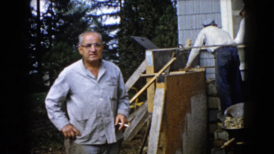 A man with glasses and a cigarette faces the camera near an outdoor house foundation project in Wauconda, Illinois, in 1960.