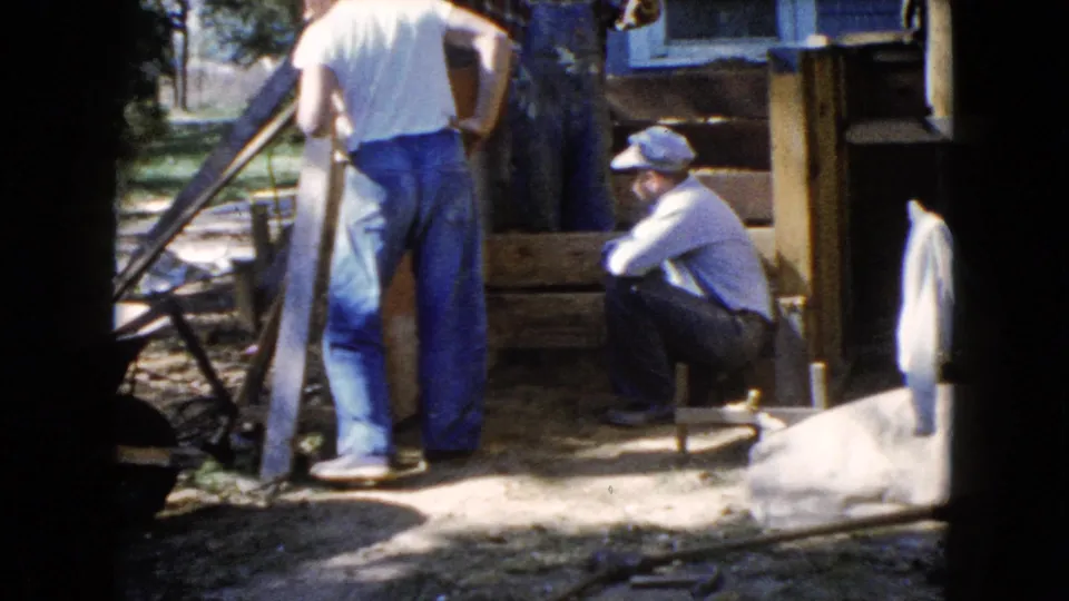 In the final frame, one man holds a shovel and another crouches near a partly framed outdoor area beside a house in Wauconda, Illinois.