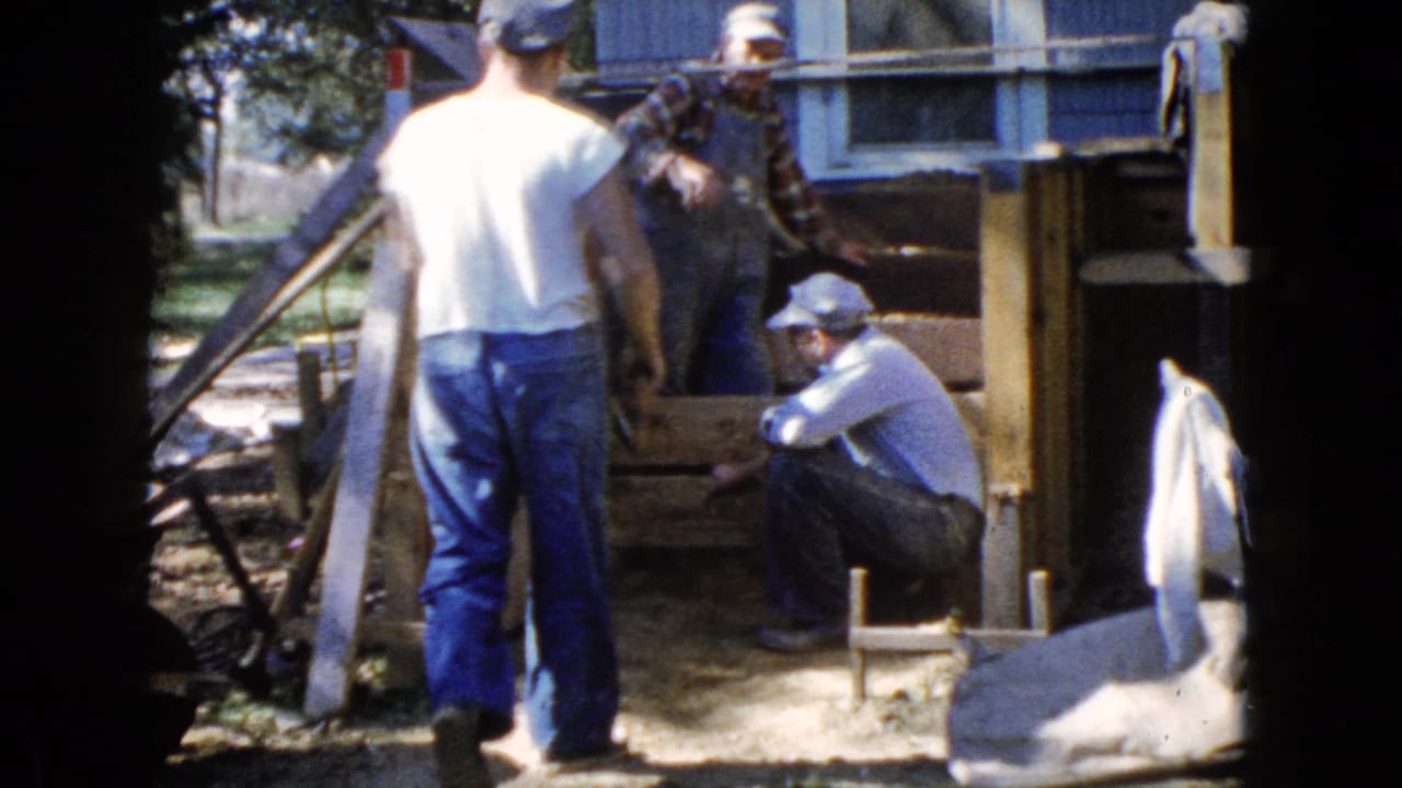 In 1960 Wauconda, Illinois home-movie footage, three adult men gather around a partially rebuilt wooden deck outside a house.