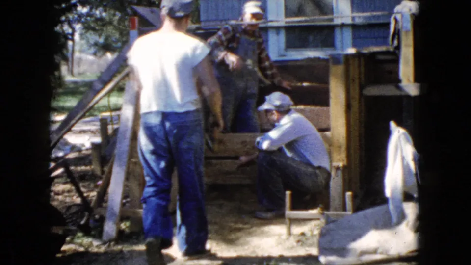 In 1960 Wauconda, Illinois home-movie footage, three adult men gather around a partially rebuilt wooden deck outside a house.
