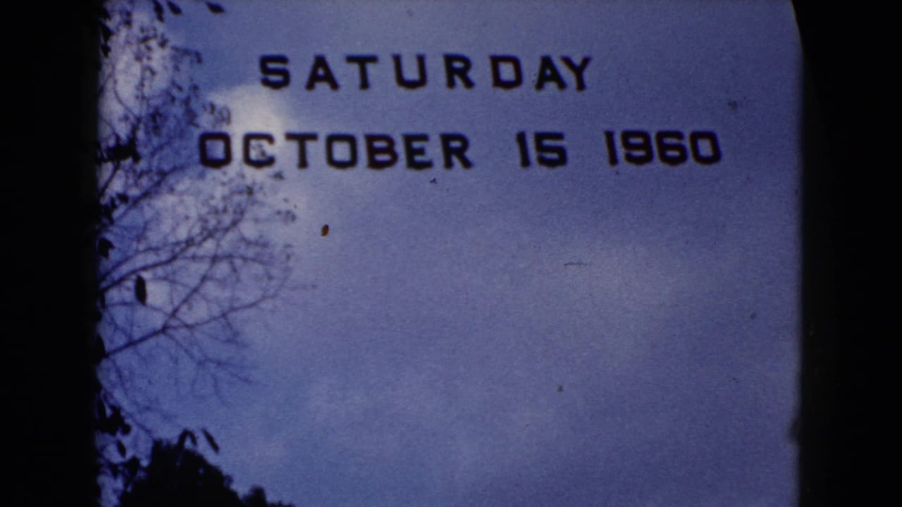 1960 home-movie title card reading Saturday October 15 1960, framed by blue sky and dark tree silhouettes.