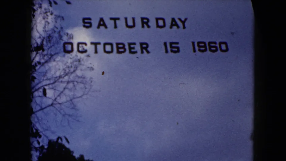 1960 home-movie title card reading Saturday October 15 1960, framed by blue sky and dark tree silhouettes.